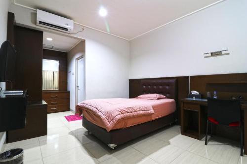 Dormitorio con cama, escritorio y TV en Bendungan Hilir Residence en Yakarta