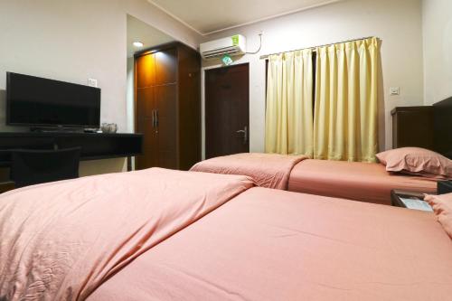 a room with two beds and a flat screen tv at Bendungan Hilir Residence in Jakarta