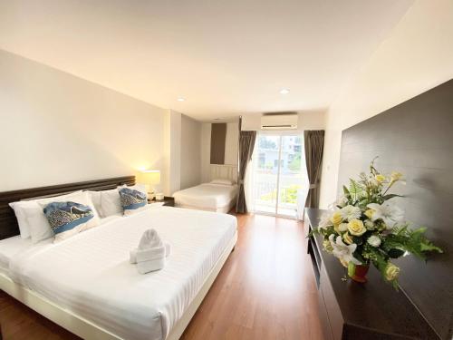 - une chambre avec un grand lit blanc et un vase de fleurs dans l'établissement 14 Place Sukhumvit Suites, à Bangkok