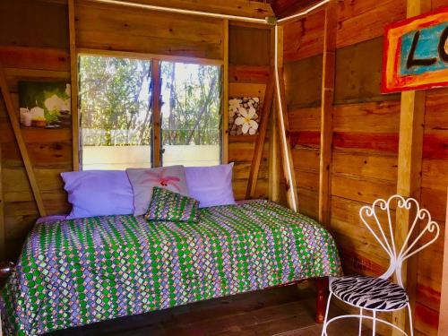 a bedroom with a bed and a window in a cabin at Moringa Ingadi in Treasure Beach