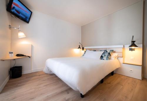 a bedroom with a white bed and a tv on the wall at Hotel Little Regina in Paris