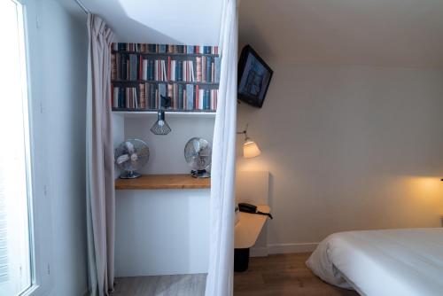 a bedroom with a bed and a book shelf with books at Hotel Little Regina in Paris