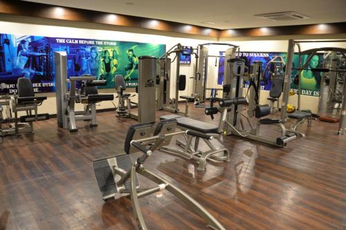 a gym with several tread machines and a large screen at Jacaranda Heights in Islamabad