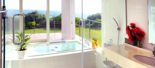 a bathroom with a tub in a window at wisteria Ocean Nakijin in Nakijin