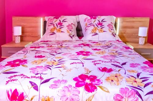 Bett mit Blumenbettdecke und Kissen darauf in der Unterkunft Le Tuit-Tuit **** in Sainte-Suzanne