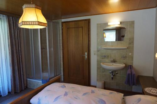 sypialnia z łóżkiem, umywalką i lampką w obiekcie Gästehaus Metzler w mieście Bizau