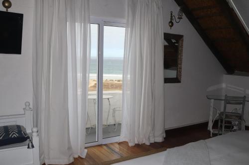 a bedroom with a window with a view of the ocean at Gilcrest Place Guest House in Paternoster