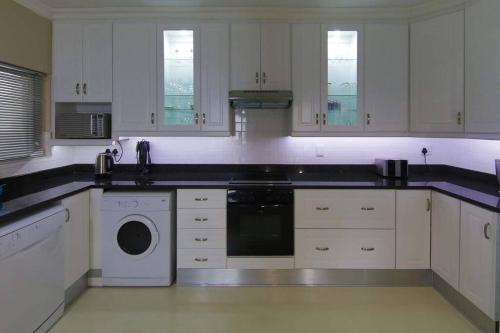 a large kitchen with white cabinets and a dishwasher at 602 MARBELLA UMHLANGA DURBAN in Durban