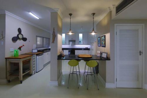 a kitchen with two bar stools and a counter at 602 MARBELLA UMHLANGA DURBAN in Durban