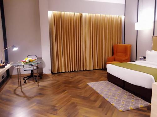 a bedroom with a bed and a desk and a table at Hotel Polo Towers Agartala in Agartala