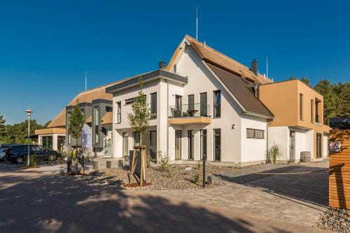a white building with trees in front of it at Düne 74 in Ostseebad Karlshagen