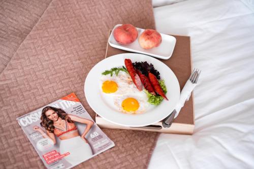 テルノーピリにあるHotel Halychynaの卵・野菜の朝食プレートと雑誌