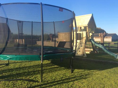um parque infantil com um trampolim na relva em B&B Quarterhouse em Moerkerke