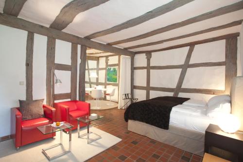 a bedroom with a bed and two red chairs at Mühle am Schlossberg in Wartenberg-Rohrbach