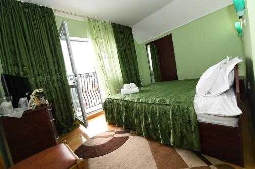 a bedroom with a green bed and a window at Villa Nina in Câmpina