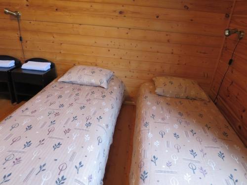 two beds in a room with wooden walls at Männi Farm Holiday House in Eoste