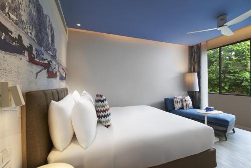 a hotel room with a bed and a window at OZO Phuket in Kata Beach