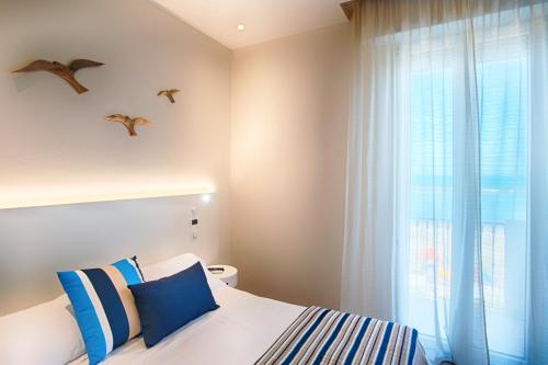 a bedroom with a bed and a window with birds on the wall at Hotel Agostini in Bellaria-Igea Marina