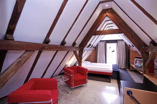 a attic room with a bed and red chairs at Mühle am Schlossberg in Wartenberg-Rohrbach