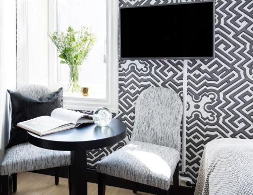 a living room with a table and two chairs and a tv at Frogner House - Bygdøy Allé in Oslo