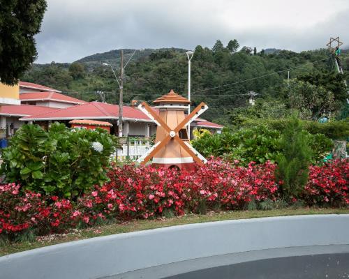 a house with a windmill and flowers on the side of a road at Panama Camping Park Boquete in Boquete