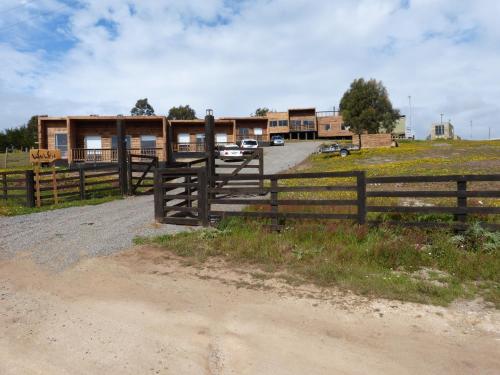 une clôture sur un chemin de terre devant un bâtiment dans l'établissement Waiwen, à Pichilemu