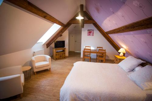 a attic room with a bed and a table and chairs at Au murier in Goxwiller