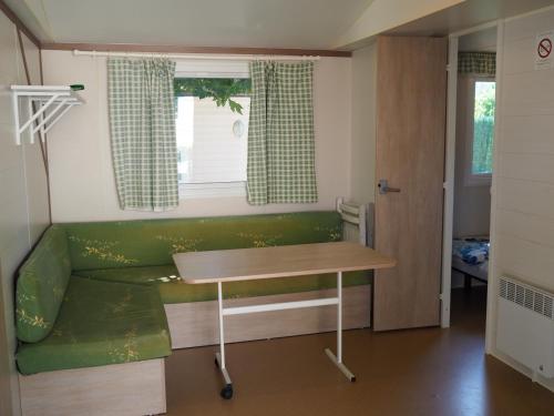 Cette petite chambre comprend un canapé vert et une table. dans l'établissement LE CASQUE ROI, à Salavas