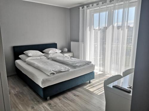 een slaapkamer met een bed en een groot raam bij Bryant - Pokoje & Apartamenty in Władysławowo