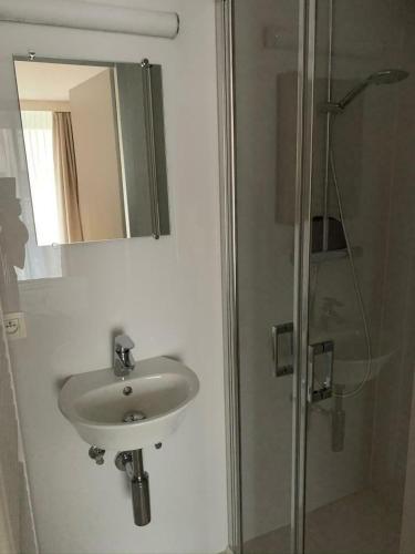 łazienka z umywalką i prysznicem z lustrem w obiekcie Zeedijk Appartement w mieście Knokke-Heist