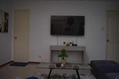 a living room with a couch and a tv on a wall at Affordable Makati APT in Manila