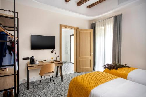 um quarto de hotel com uma cama, uma secretária e uma televisão em Cal Roure Boutique Hotel em Igualada