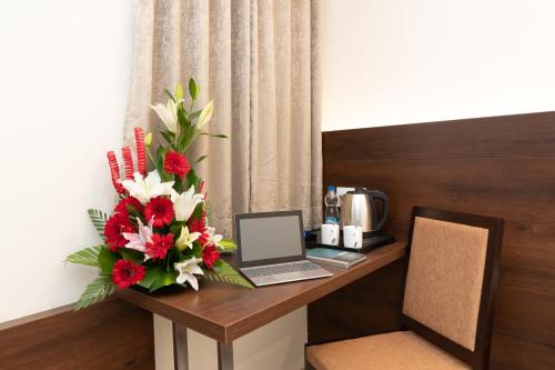 a desk with a laptop and a bouquet of flowers at Mojatel By Icon in Bengaluru