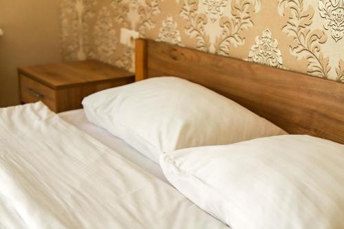 a bed with white sheets and a wooden headboard at Hotel LaMa 2 in Kyiv