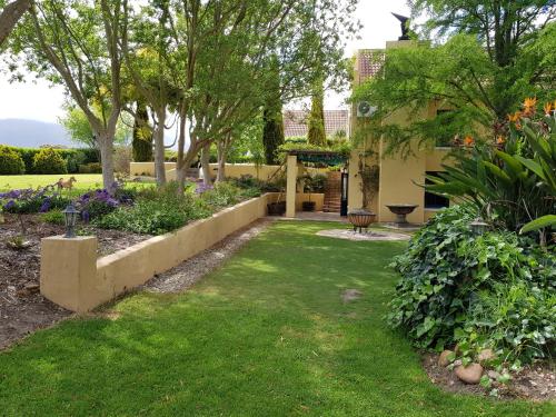a garden with green grass and purple flowers at Villa Tarentaal in Tulbagh