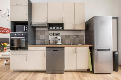 une cuisine avec des appareils en acier inoxydable et des armoires blanches dans l'établissement Grand appartement avec 3 salles de bain, à Tourcoing