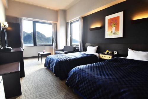 a hotel room with two beds and a window at Miyajima Coral Hotel in Miyajima