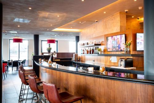 a bar in a restaurant with a counter and chairs at Bastion Hotel Brielle - Europoort in Brielle