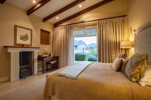 Schlafzimmer mit einem Bett, einem Kamin und einem Fenster in der Unterkunft La Cabriere Country House in Franschhoek