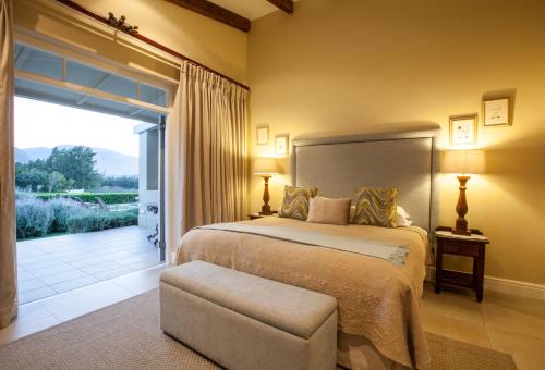 a bedroom with a bed and a sliding glass door at La Cabriere Country House in Franschhoek