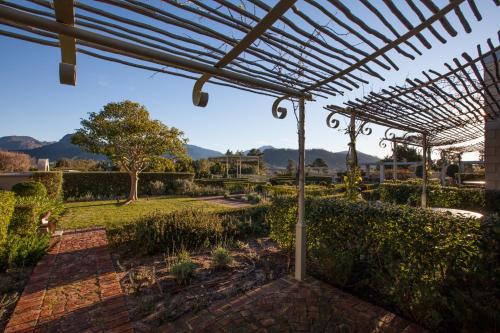 a pergola with a view of a garden at La Cabriere Country House in Franschhoek