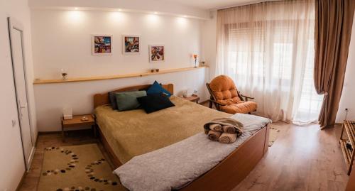 a bedroom with a large bed and a chair at Apartmani Jovčić in Leskovac