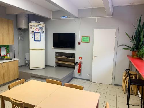 a kitchen with a table and a refrigerator and a tv at Vyborghostel in Vyborg