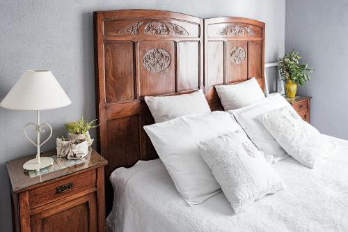 a bedroom with a large wooden bed with white pillows at Villa Curte Nicia in Nizza Monferrato