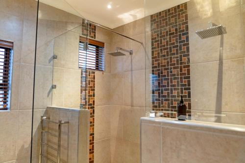 a bathroom with a shower with a glass door at Boplaas Guesthouse in Op-die-Berg