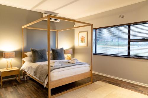 a bedroom with a canopy bed and a window at Boplaas Guesthouse in Op-die-Berg