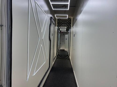 a hallway in a train with white walls and a long aisle at AV-1 Capsule Hotel in Kyiv