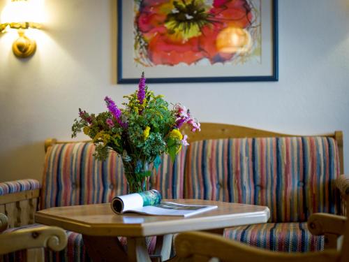 a table with a vase of flowers and a book at Zum Kirchenwirt in Lam