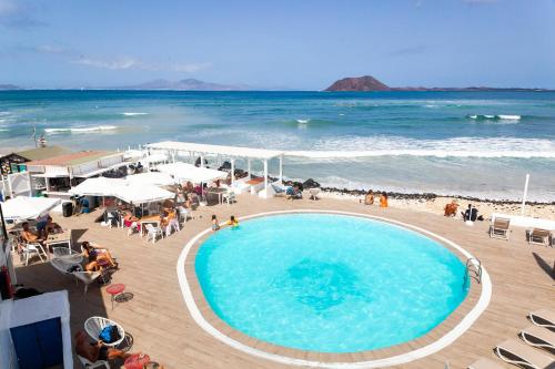 a large swimming pool on a beach next to the ocean at Apartamentos Punta Elena Beach in Corralejo