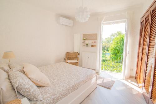 a white bedroom with a bed and a large window at SARA E MELISSA HOUSE LIERNA in Lierna